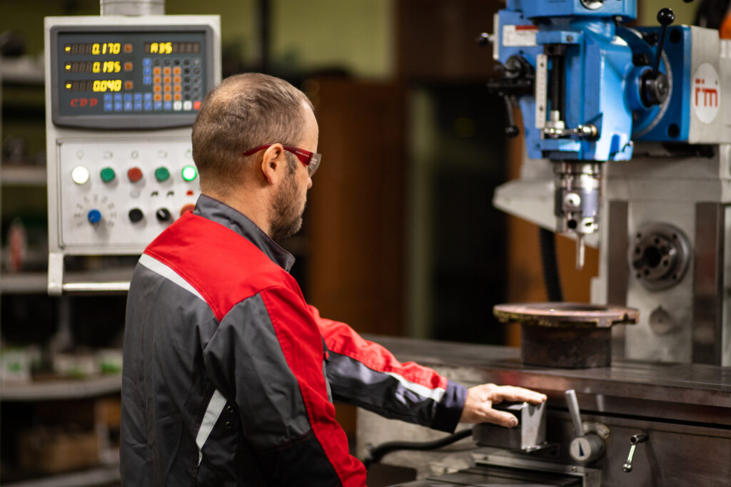 stotz brest 1 Работник в красно-черной униформе и защитных очках управляет синим промышленным станком