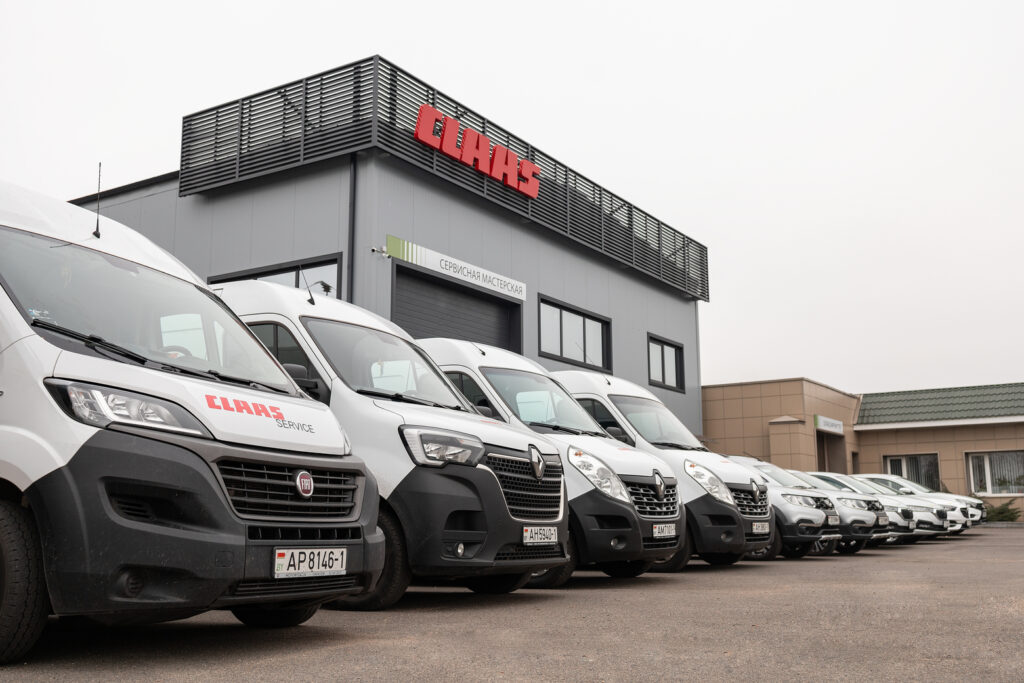 stotz brest 4 Ряд белых автомобилей припаркован перед зданием сервисной мастерской Штотц Агро-Сервис в Бресте. На здании над гаражными воротами располагается вывеска CLAAS